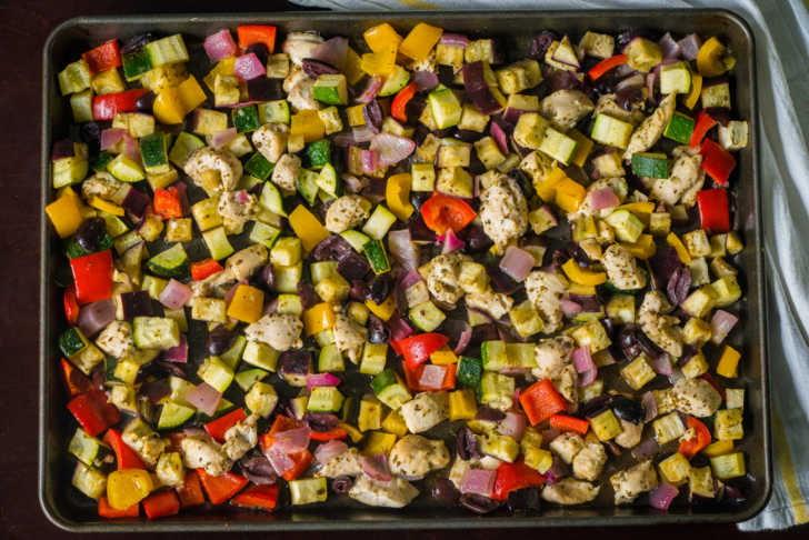 Top down of sheet pan with chicken and diced greens and veggies