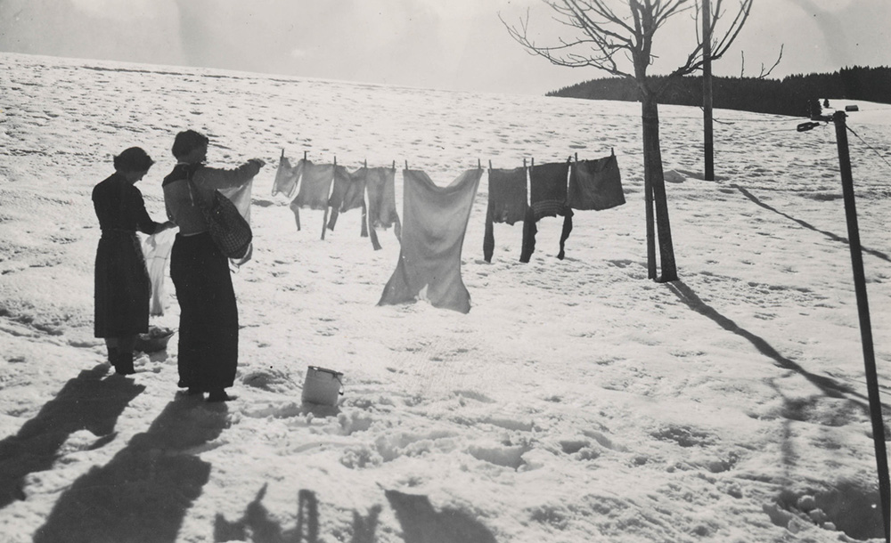 black and white photo of two women hanging out laundry in the snow