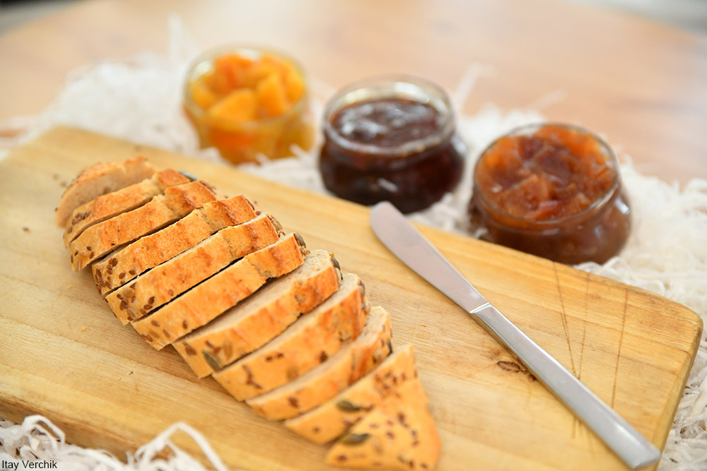 selection of jams and jellies next to a loaf of sliced bread