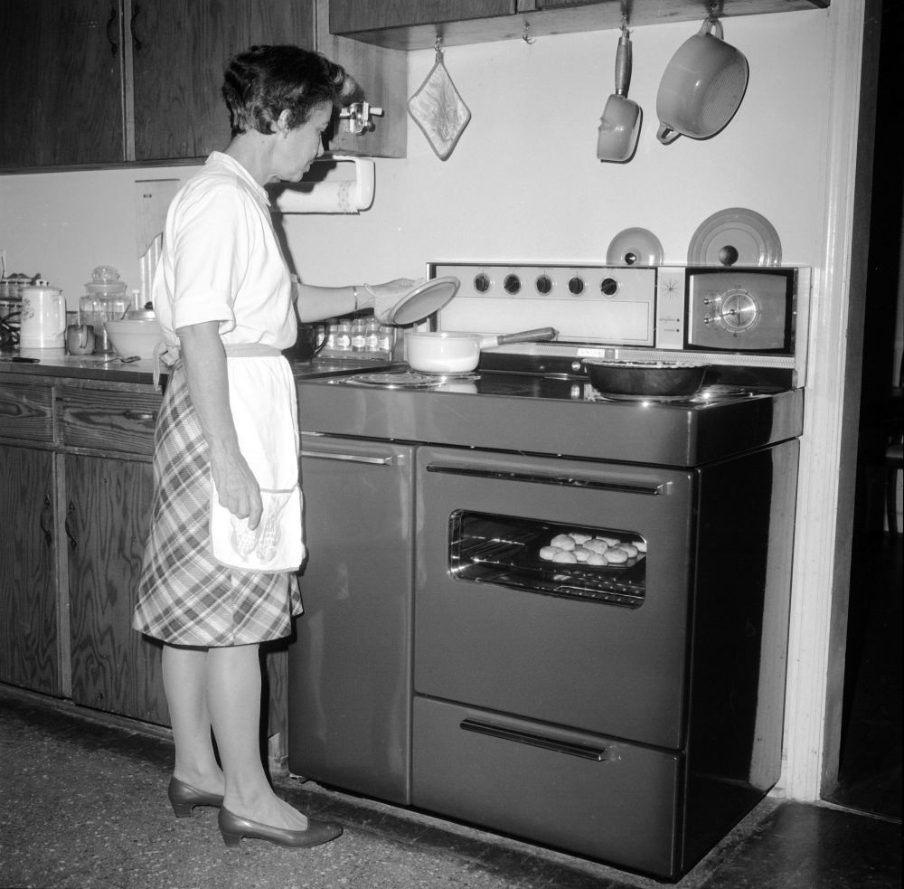 woman cooking over a stove, 1950s or 1960s
